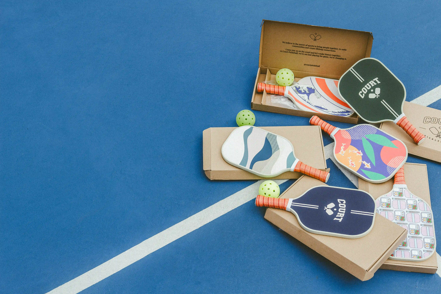 beautiful asian inspired pickleball paddles laying on pickleball court
